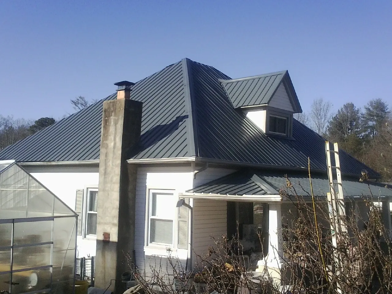 Dark blue standing seam metal roof on a white farmhouse with dormer — Slate & Tile Roof Repair by Roofing Brothers in Rindge