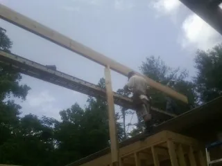 Carpenter setting a ridge beam over a new addition frame — Ice Dam Removal by Roofing Brothers in Rindge