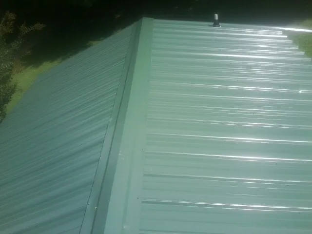 New green metal panels meeting at the ridge of a roof — Flat Roof Repair work by our crew in Rindge