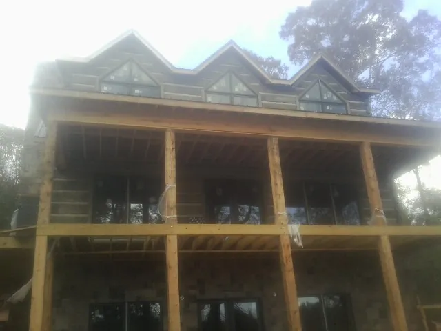 Dormers and porch framing on a large log home under construction — Roof Coating work by our crew in Rindge