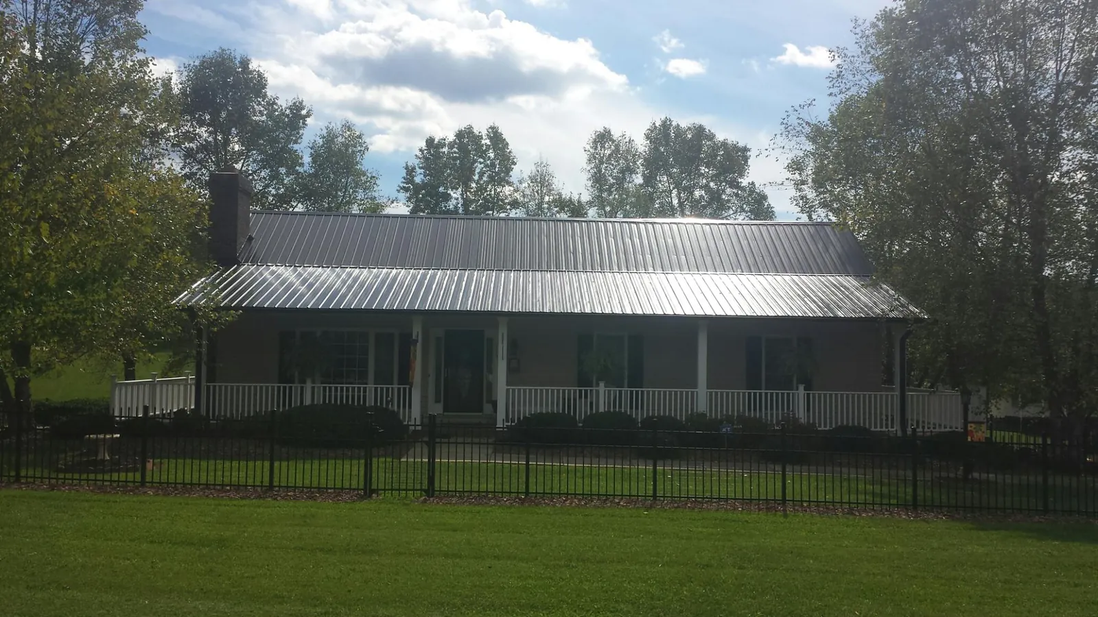 Gray metal roof on a brick ranch with a full width front porch — Gutter Guard Installation work by our crew in Rindge