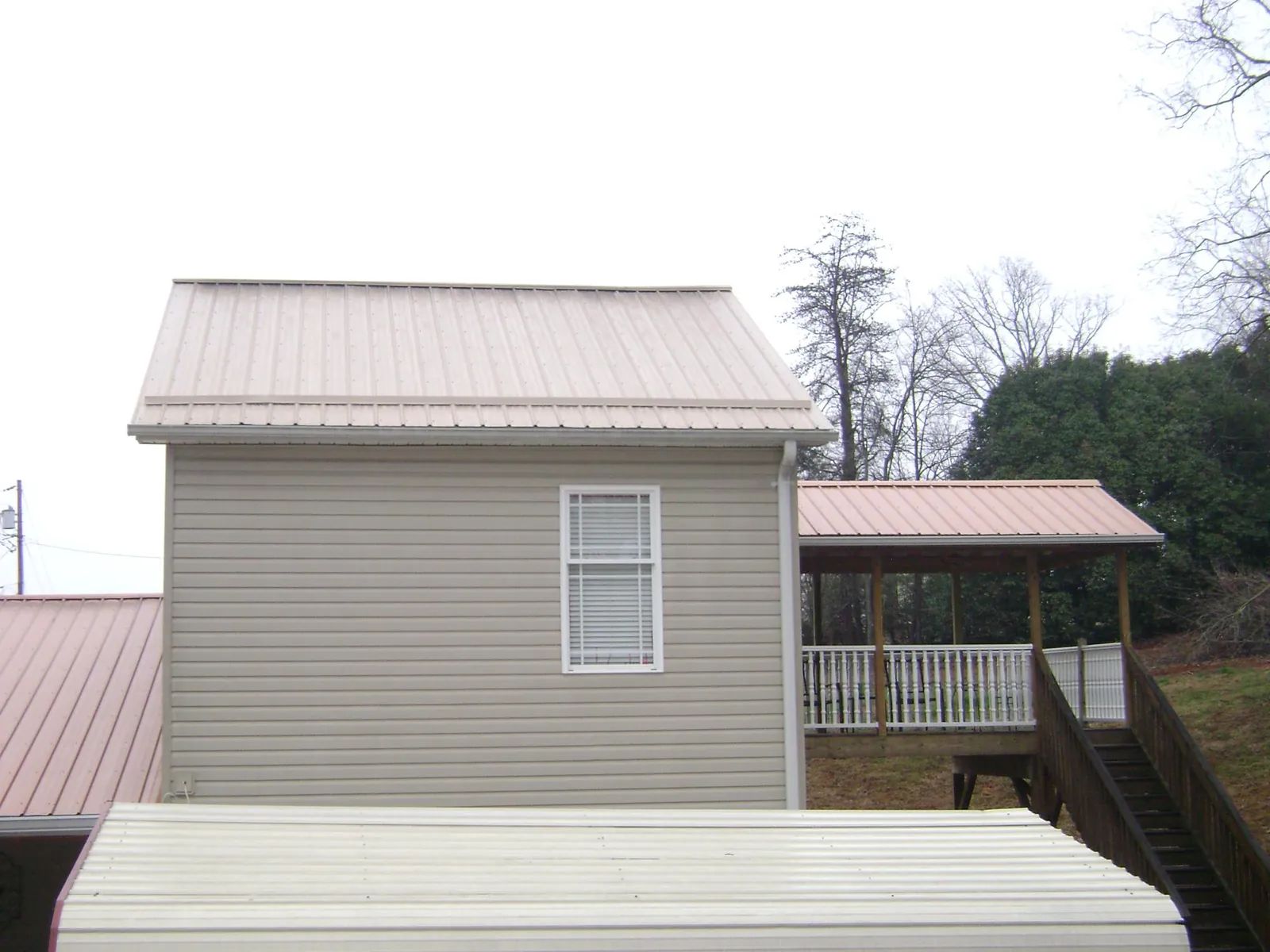 Tan metal roofs on a two story addition and attached porch, from a Roof Replacement job in Rindge