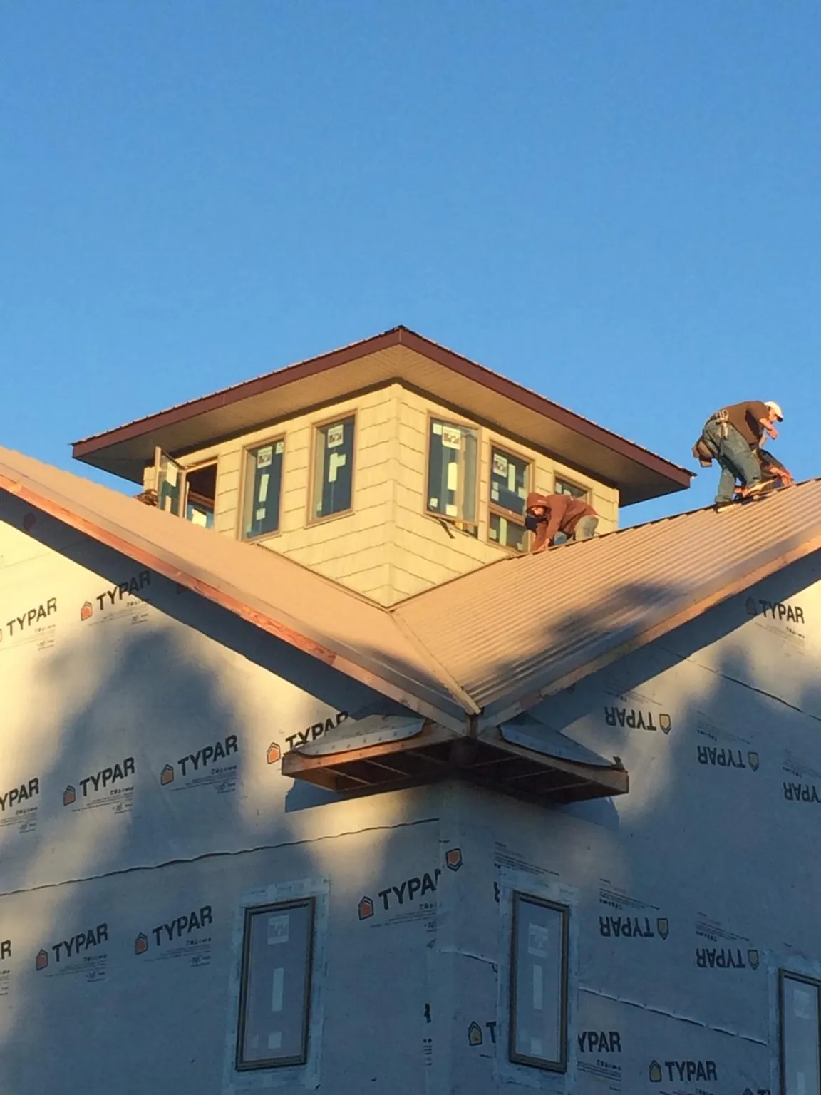Roofers working around a rooftop cupola on a new metal roof at sunset — Roof Waterproofing in Rindge by Roofing Brothers